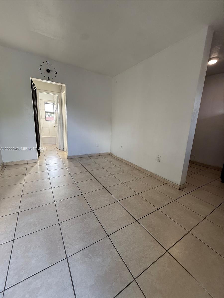 A room with light-colored tile flooring and a doorway leading to a bathroom — 3330 NW 48th Ter # 206, Miami FL 33142, MIAMI, FL