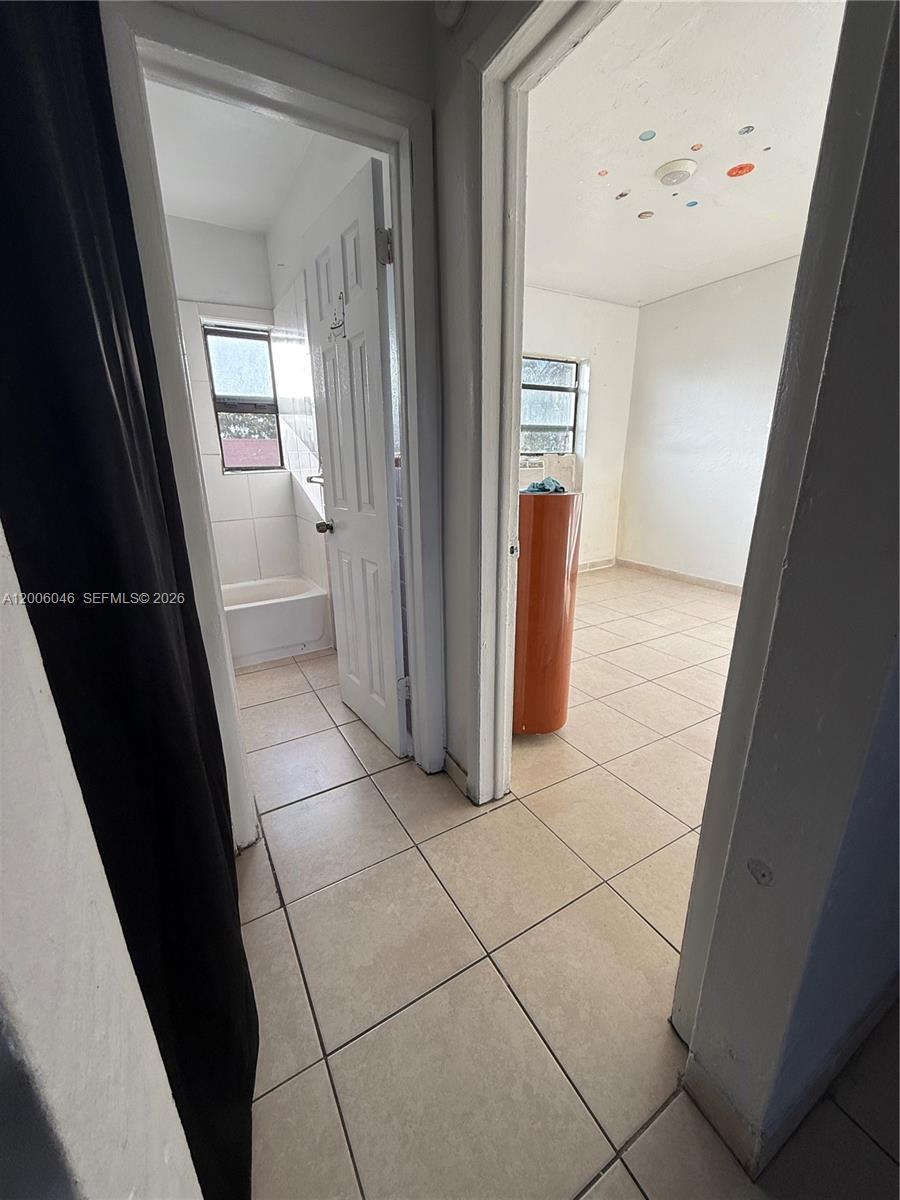 A hallway with tiled floors leads to a bathroom on the left and a bedroom — 3330 NW 48th Ter # 206, Miami FL 33142, MIAMI, FL