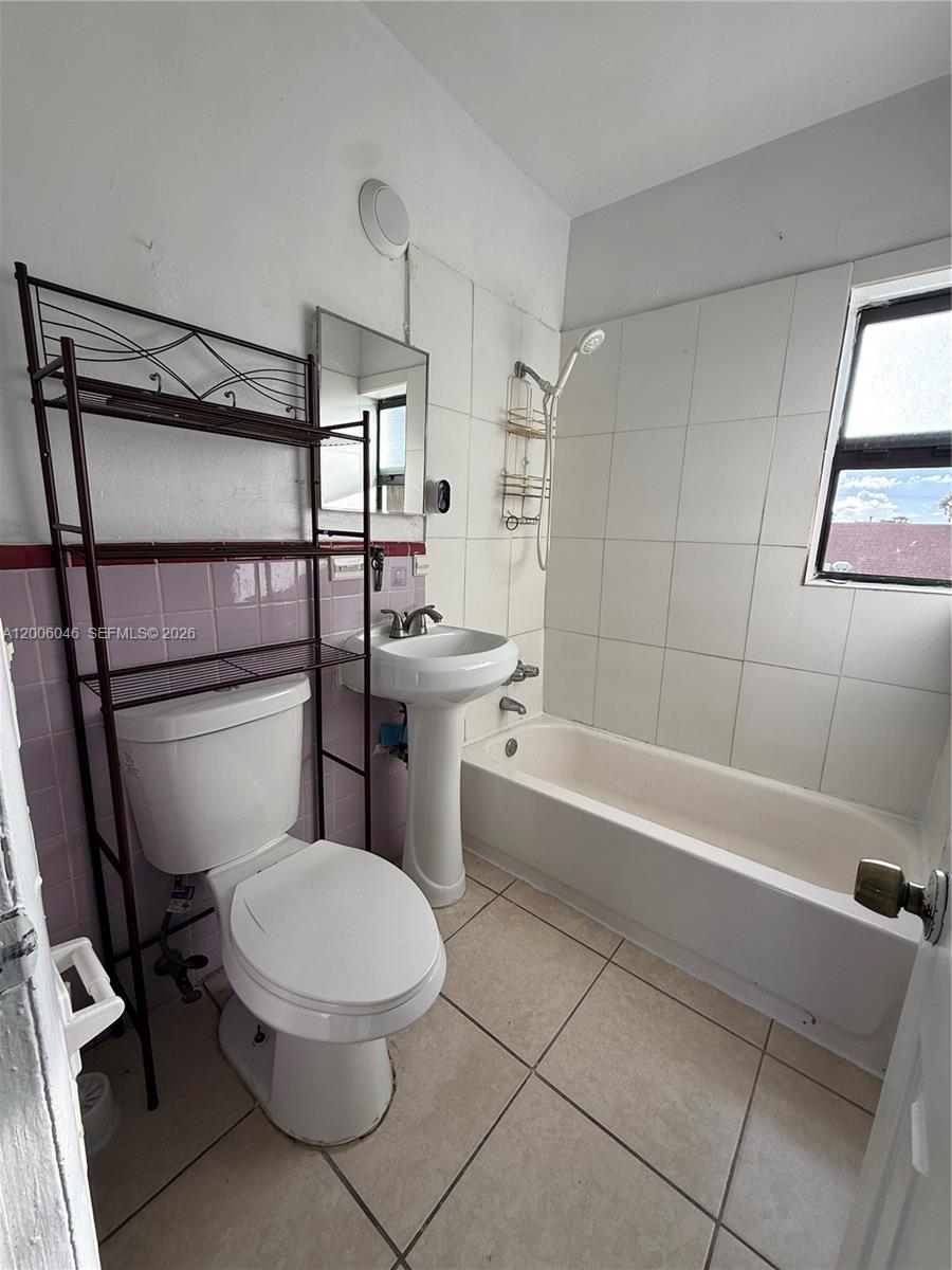 A bathroom features a pedestal sink, a toilet with a metal shelf, and a tub — 3330 NW 48th Ter # 206, Miami FL 33142, MIAMI, FL