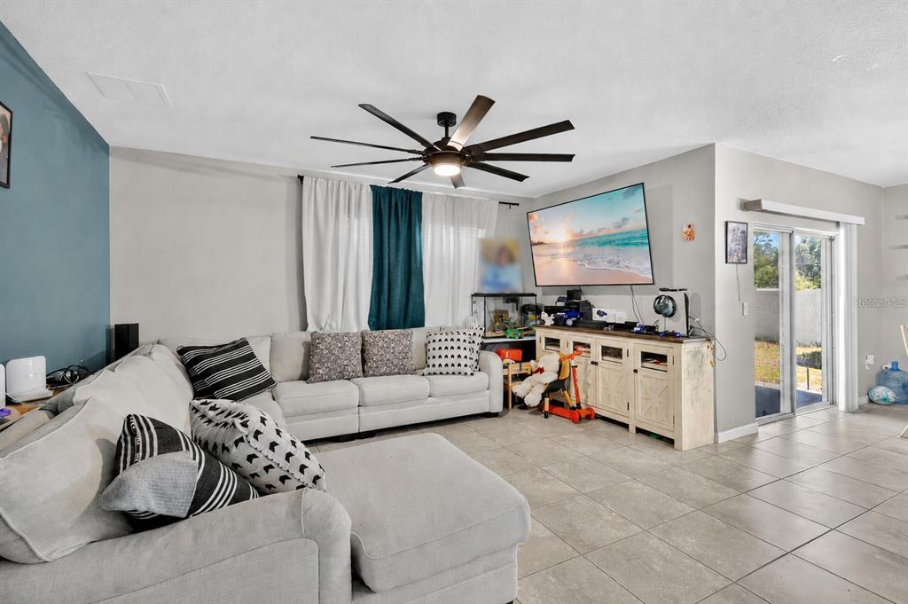 A living room features a large sectional sofa, a wall-mounted television, and tile flooring — 941 CENTURY AVENUE SE, PALM BAY, FL