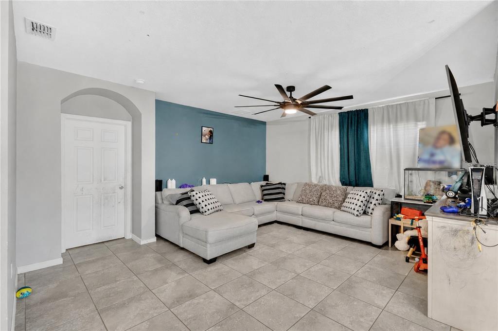 A living room features a light gray sectional sofa, a blue accent wall, and tile flooring — 941 CENTURY AVENUE SE, PALM BAY, FL