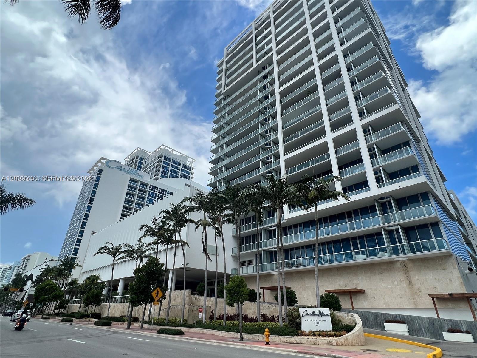 A low-angle exterior view of the Carillon Miami Wellness Resort featuring two modern high-rise buildings — 6799 Collins Ave # 1501, Miami Beach FL 33141, MIAMI BEACH, FL