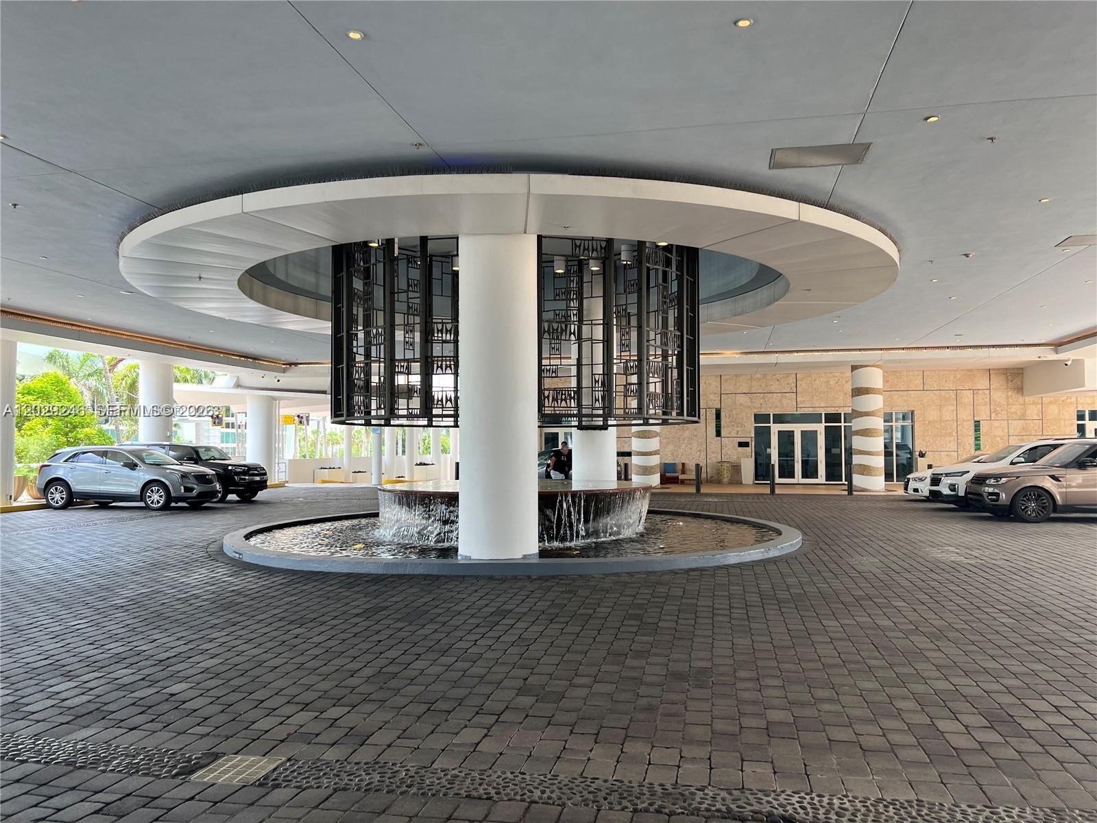 A circular fountain with a decorative metal screen sits under a large porte-cochère — 6799 Collins Ave # 1501, Miami Beach FL 33141, MIAMI BEACH, FL