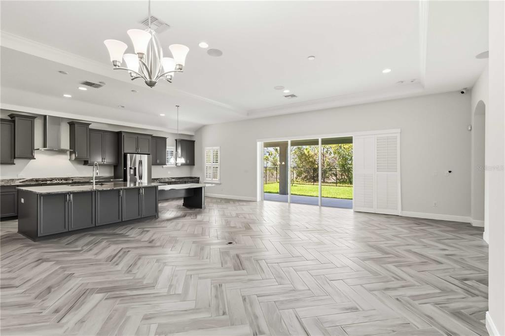 A kitchen with dark gray cabinets and a large island overlooks a living area — 6404 MAIDEN SEA DRIVE, APOLLO BEACH, FL