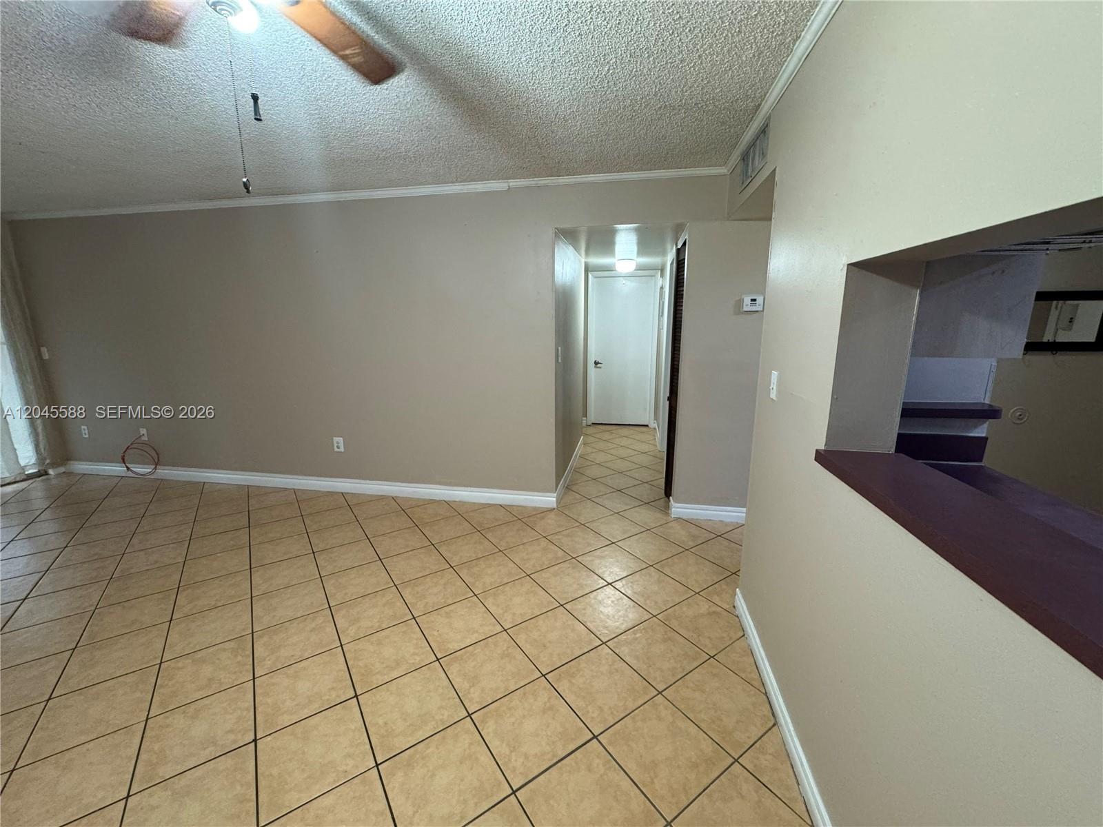 A living area features beige walls, tan tile flooring, a ceiling fan, and a pass-through window — 10865 SW 112th Ave # 105, Miami FL 33176, MIAMI, FL