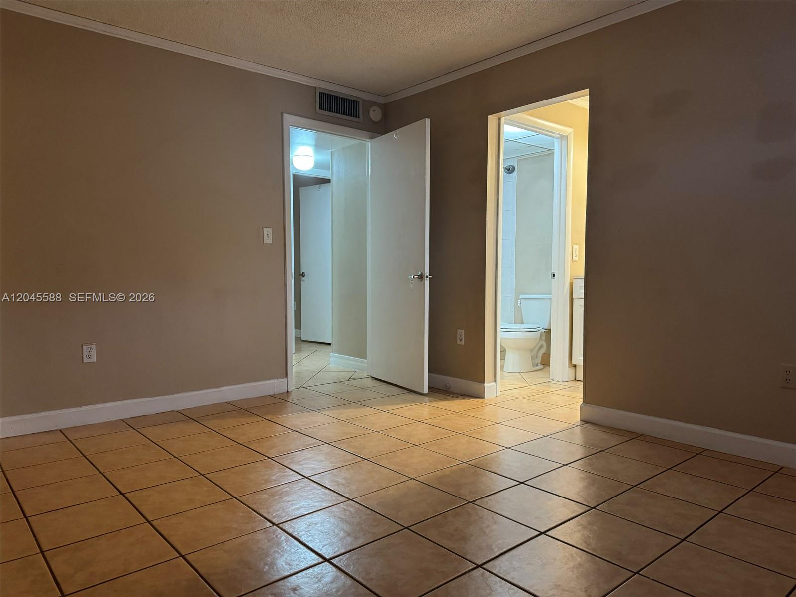 A room with tan tile flooring features two doorways leading to a bathroom and hallway — 10865 SW 112th Ave # 105, Miami FL 33176, MIAMI, FL