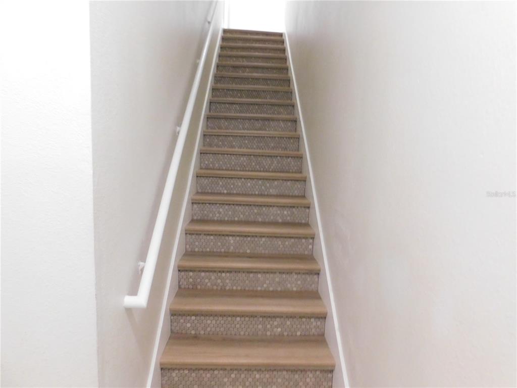A straight staircase with wood-look treads and mosaic tile risers between two white walls — 417 SOUTHERN PECAN CIRCLE UNIT 201, WINTER GARDEN, FL