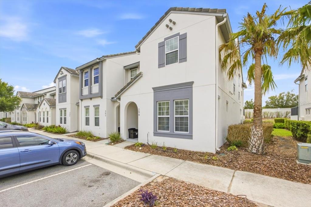 A two-story townhouse with white stucco walls, grey trim, and a palm tree outside — 298 CAPTIVA DRIVE, DAVENPORT, FL