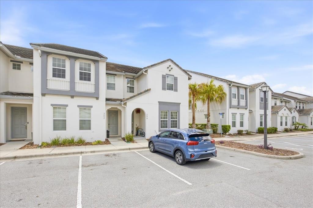 A blue car is parked in front of a multi-story townhouse complex with white siding — 298 CAPTIVA DRIVE, DAVENPORT, FL