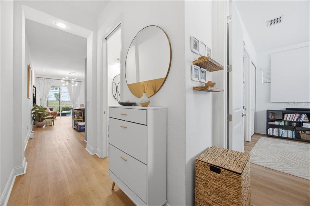 A bright hallway features light wood flooring, a white shoe cabinet, and a round mirror — 298 CAPTIVA DRIVE, DAVENPORT, FL