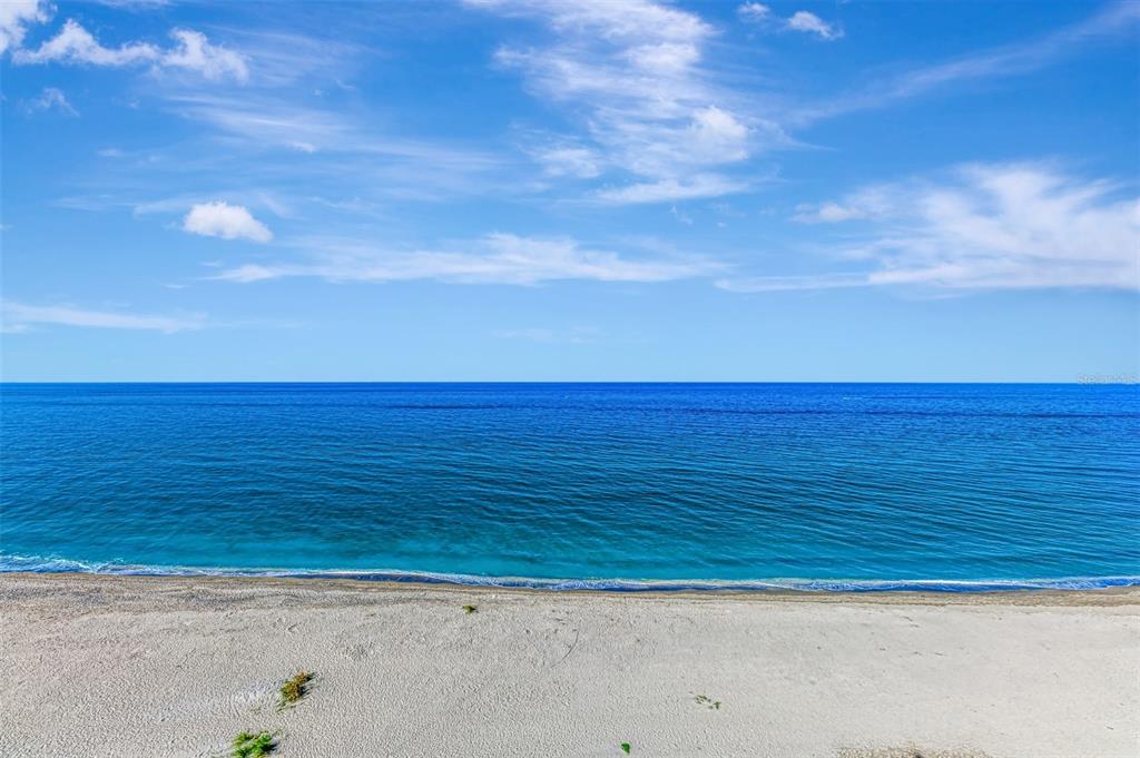 A wide-angle view of a sandy beach meeting the blue ocean under a clear sky — 631 ALHAMBRA ROAD UNIT 1004, VENICE, FL