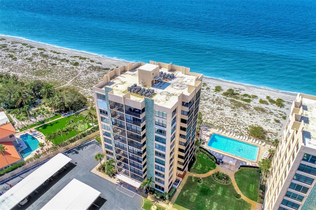 An aerial view shows a high-rise apartment building with a swimming pool near the beach — 631 ALHAMBRA ROAD UNIT 1004, VENICE, FL