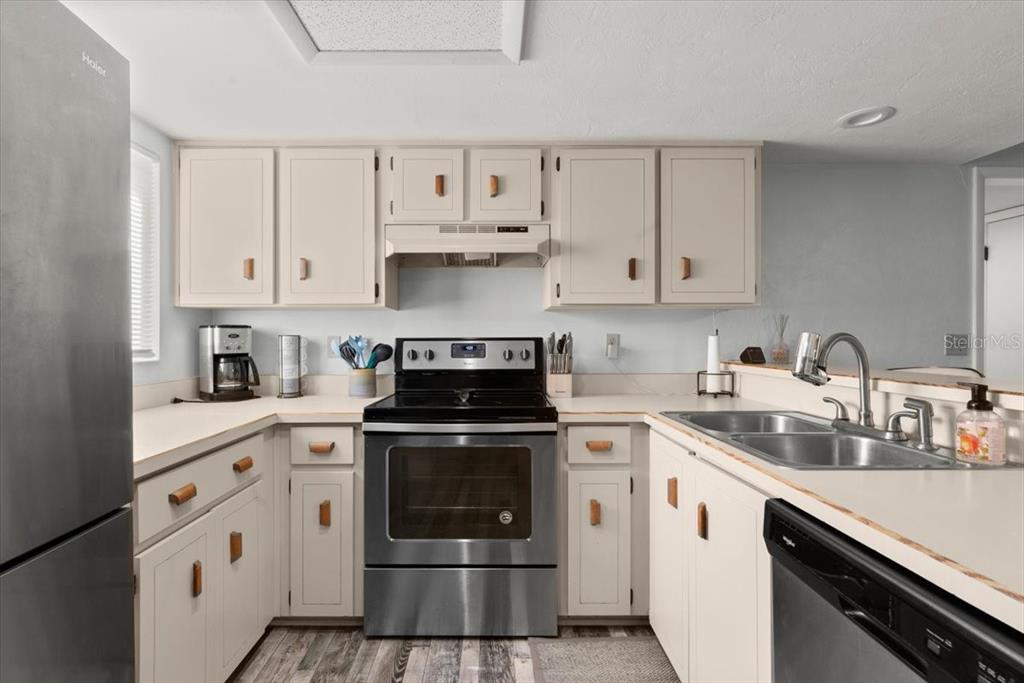 A kitchen features light-colored cabinets, stainless steel appliances, and a double-basin sink — 102 BOB WHITE COURT UNIT 102C, DAYTONA BEACH, FL