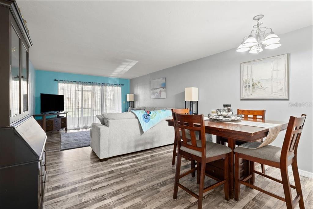 A dining area with a wooden table and chairs sits adjacent to a living room — 102 BOB WHITE COURT UNIT 102C, DAYTONA BEACH, FL