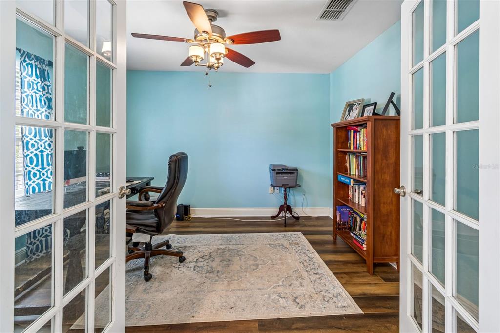 A home office with light blue walls, wood flooring, a ceiling fan, and French doors — 3216 BELLERICAY LANE, LAND O LAKES, FL