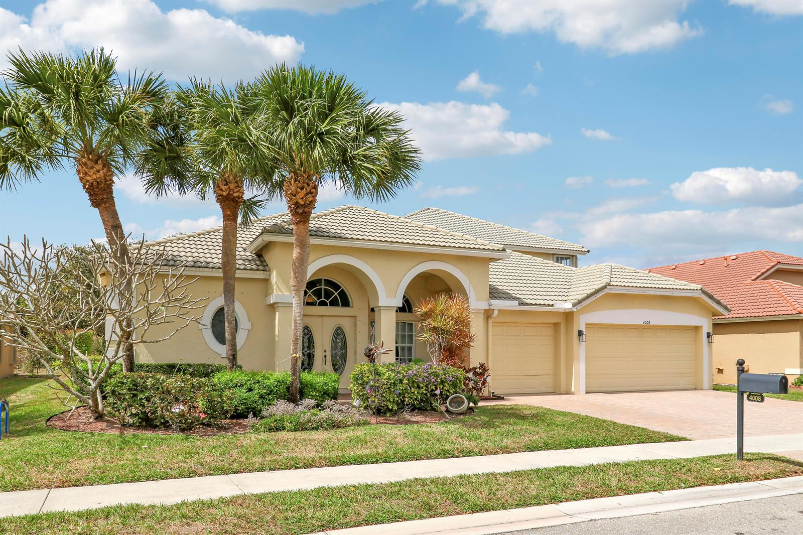 A single-story yellow stucco house with a tiled roof, two garage doors, and palm trees — 4008 W Hamilton Key, West Palm Beach FL 33411, WEST PALM BEACH, FL