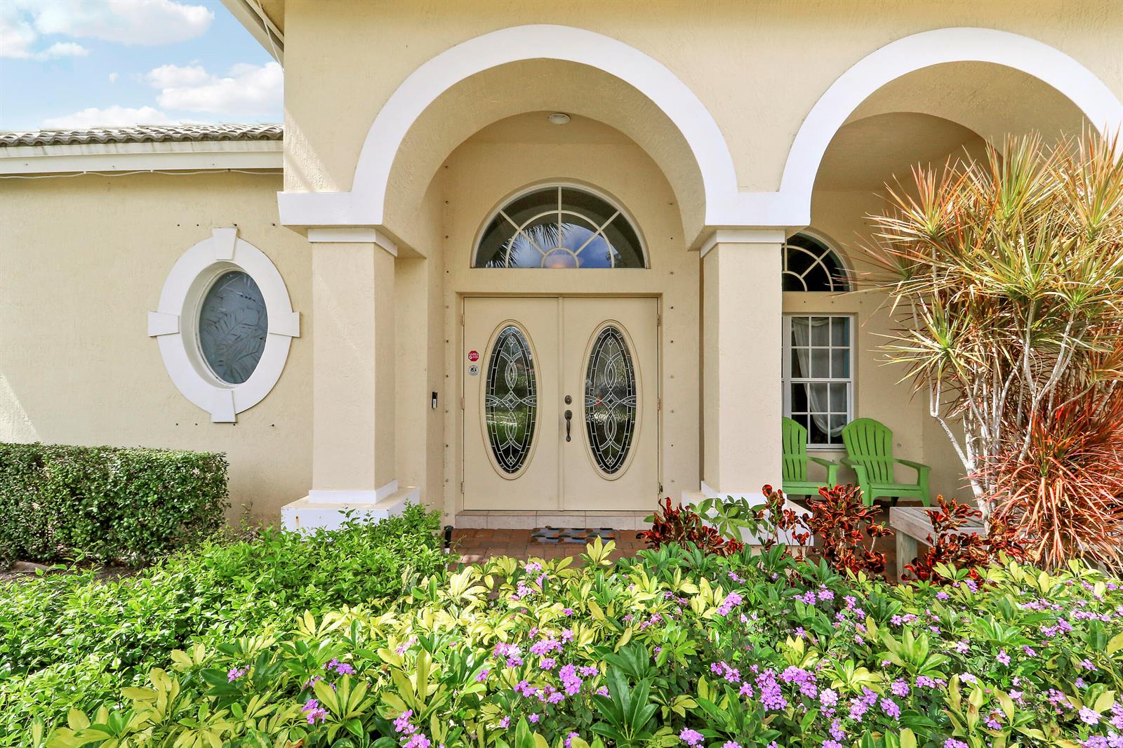 The exterior of a beige house features an arched entryway with double glass-paneled doors — 4008 W Hamilton Key, West Palm Beach FL 33411, WEST PALM BEACH, FL