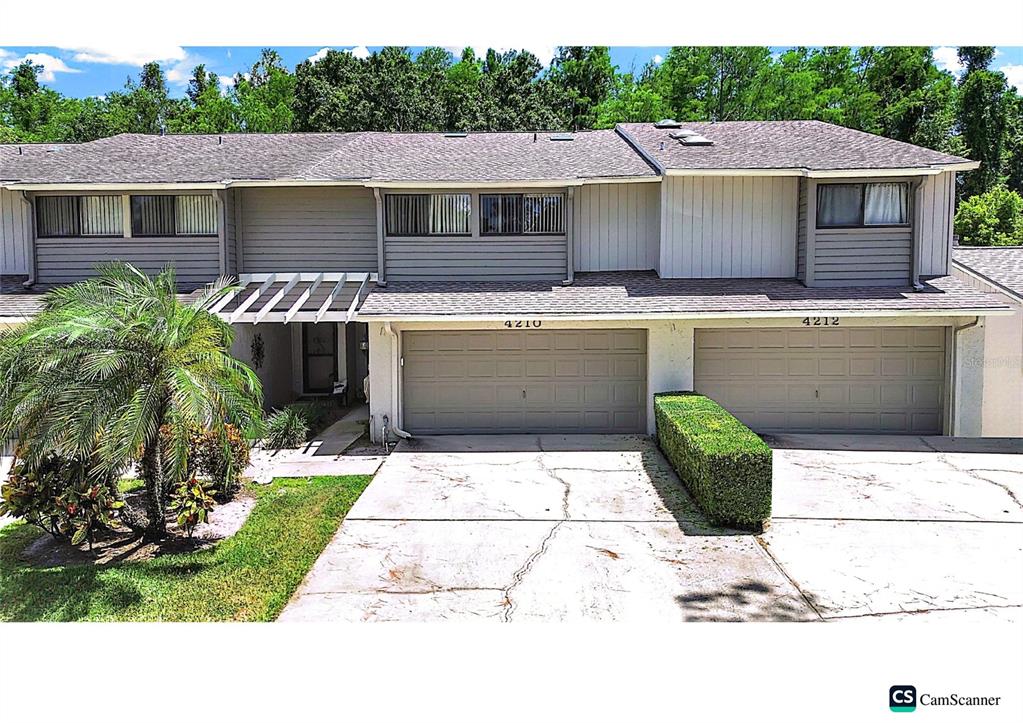 An exterior view of a two-story townhouse with two garage doors and a palm tree — 4210 FORESTER LANE, TAMPA, FL