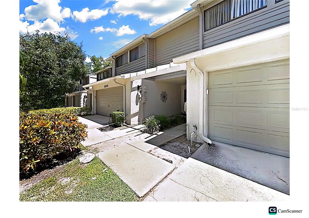A view of a two-story townhouse exterior with attached garages and a concrete walkway — 4210 FORESTER LANE, TAMPA, FL