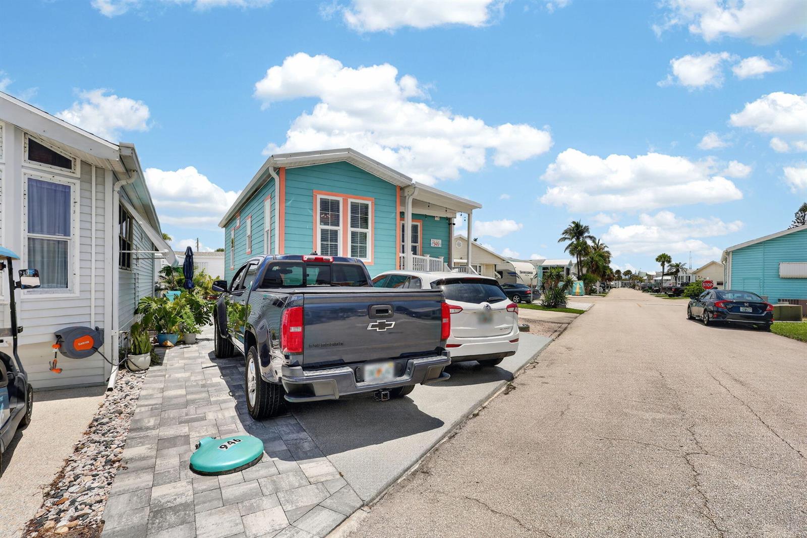 A teal house with a driveway featuring a dark pickup truck and a white SUV — 946 Nettles Boulevard, Jensen Beach FL 34957, JENSEN BEACH, FL