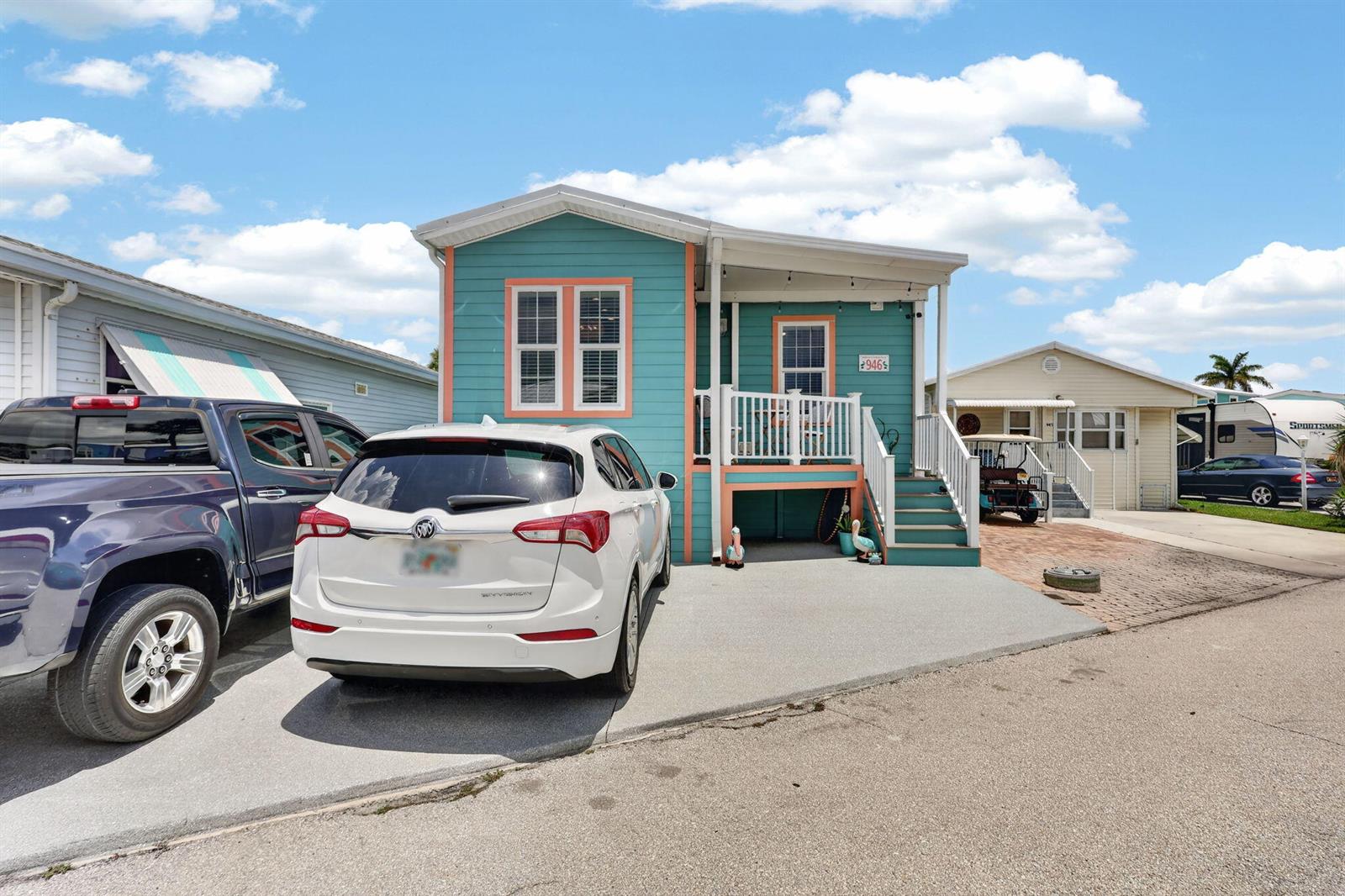 A teal house with orange trim features a front porch, stairs, and a concrete driveway — 946 Nettles Boulevard, Jensen Beach FL 34957, JENSEN BEACH, FL