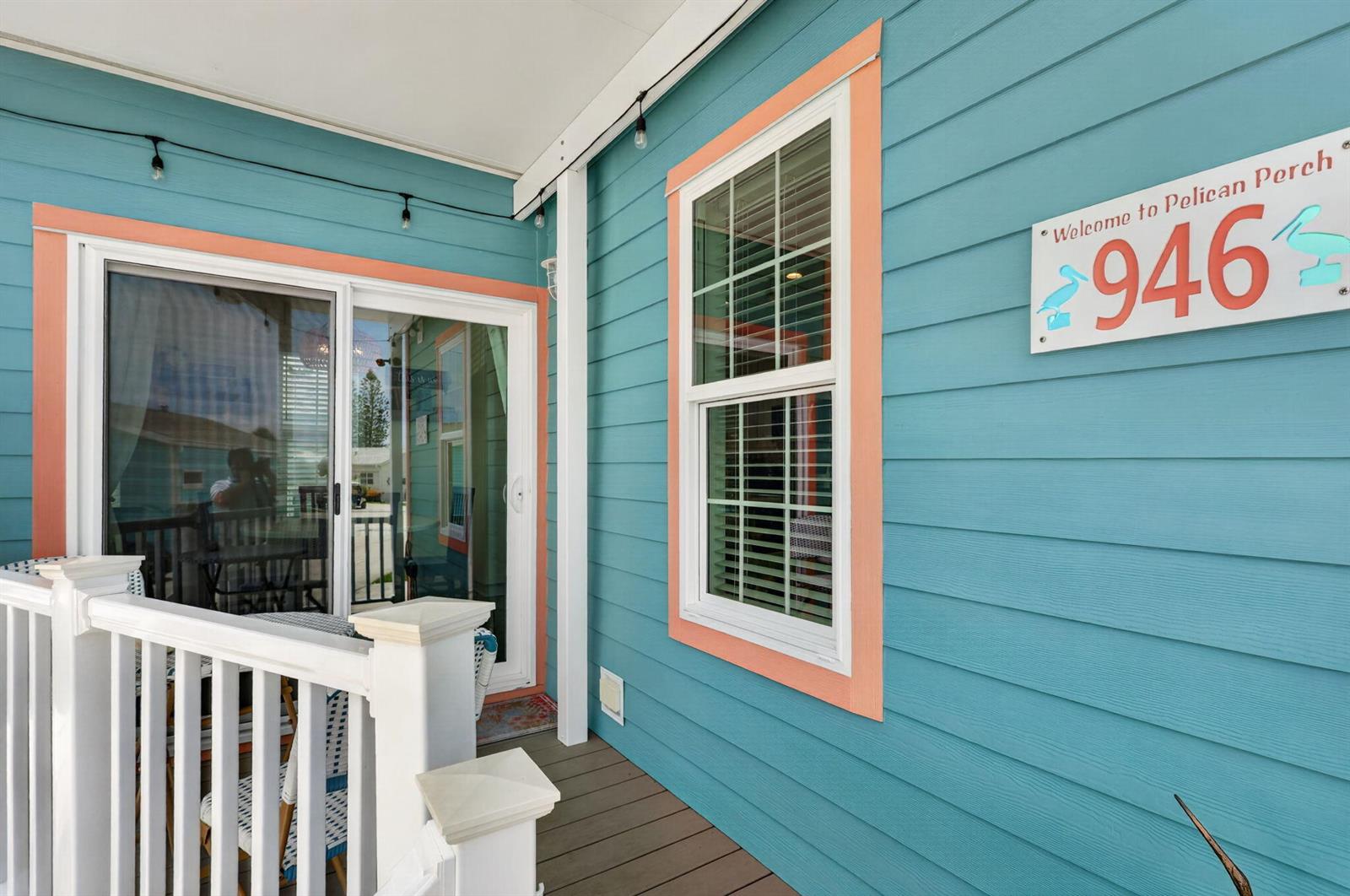 A teal-sided porch features a sliding glass door, a window, and a Pelican Perch sign — 946 Nettles Boulevard, Jensen Beach FL 34957, JENSEN BEACH, FL