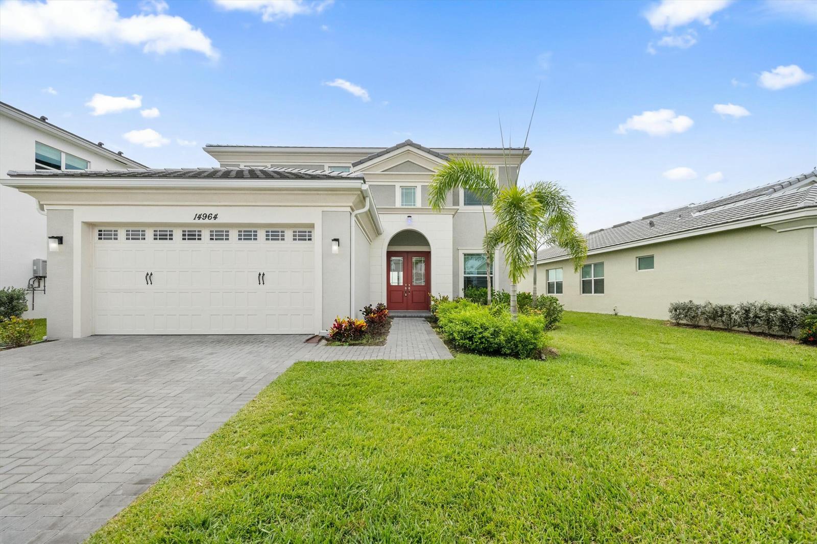 A two-story house with a white garage, red front doors, and a paved driveway — 14964 Redcove Place, Westlake FL 33470, WESTLAKE, FL