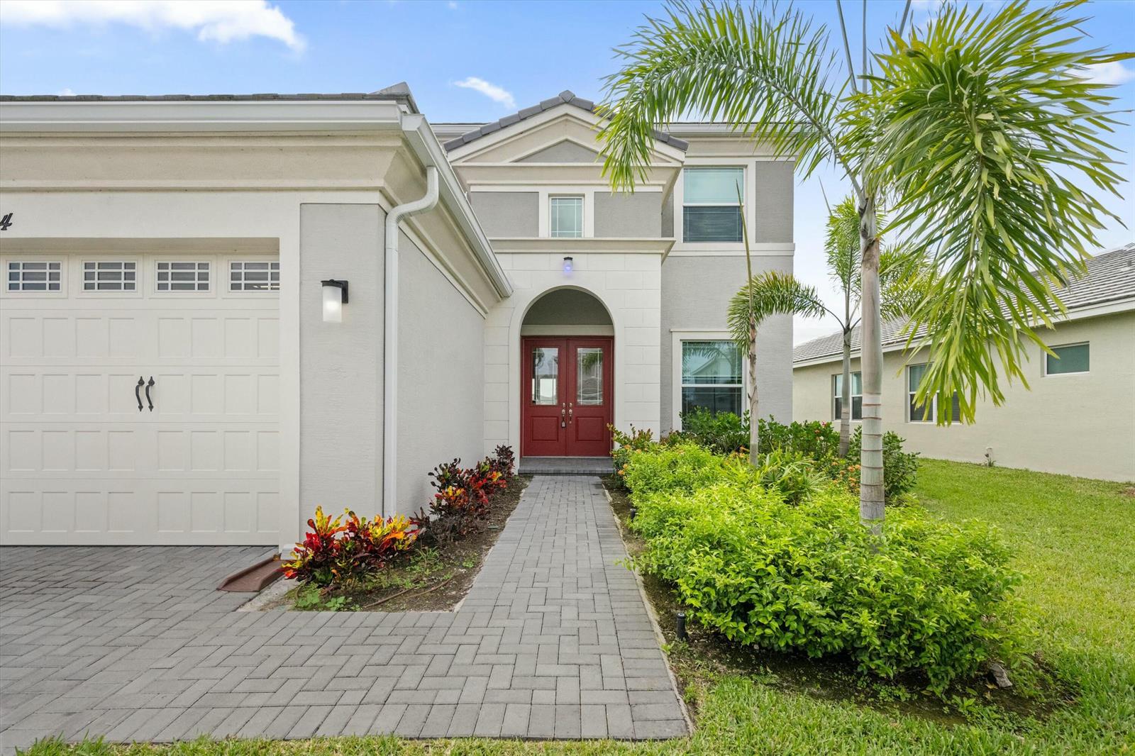 The exterior of a two-story house features a red double door and a paved walkway — 14964 Redcove Place, Westlake FL 33470, WESTLAKE, FL