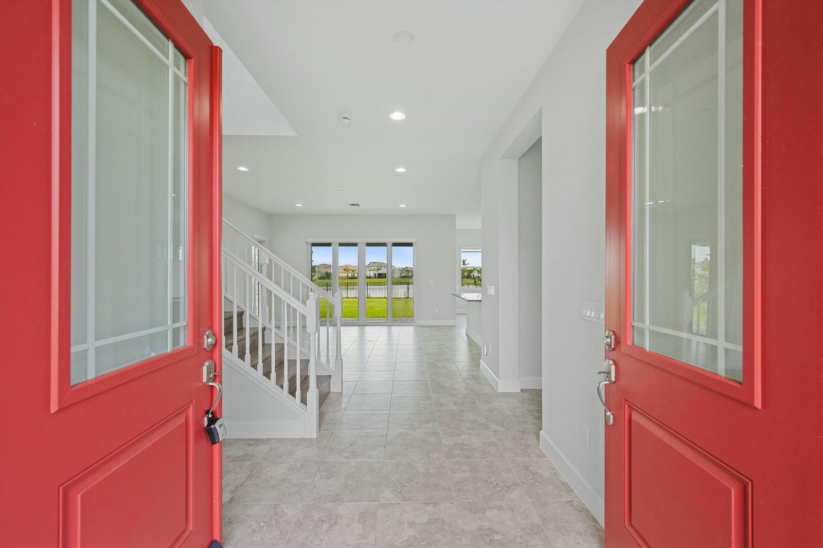 An entryway with red doors opens into a tiled foyer featuring a white staircase — 14964 Redcove Place, Westlake FL 33470, WESTLAKE, FL