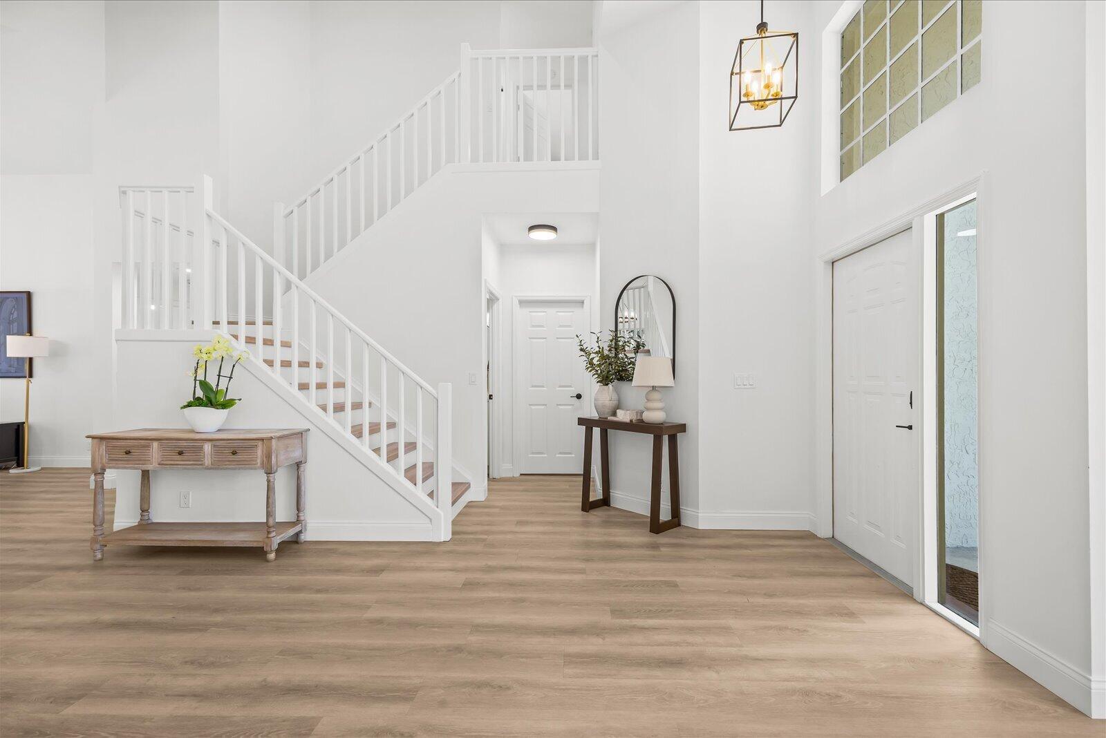 A bright foyer features light wood flooring, a white staircase, and two wooden console tables — 110 Pennock Trace Drive, Jupiter FL 33458, JUPITER, FL