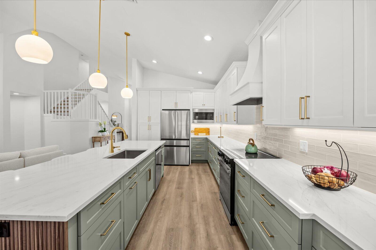 A modern kitchen features sage green lower cabinets, white upper cabinets, and a large island — 110 Pennock Trace Drive, Jupiter FL 33458, JUPITER, FL