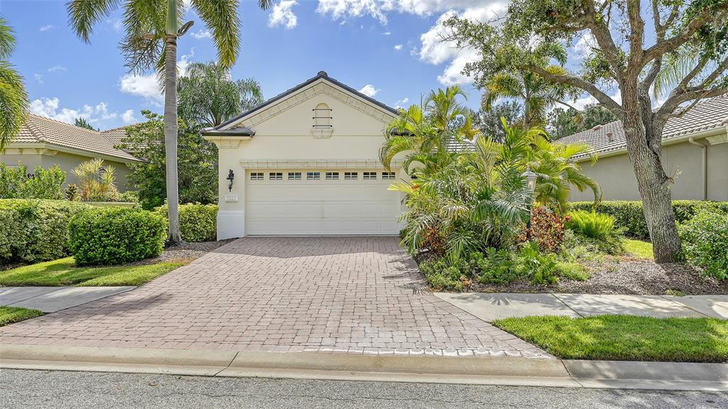 A single-story house with a beige exterior, a two-car garage, and a brick paver driveway — 7223 PRESIDIO GLEN, LAKEWOOD RANCH, FL