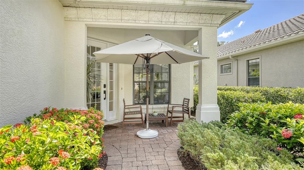 A paved patio features a white umbrella, two chairs, and a small table — 7223 PRESIDIO GLEN, LAKEWOOD RANCH, FL