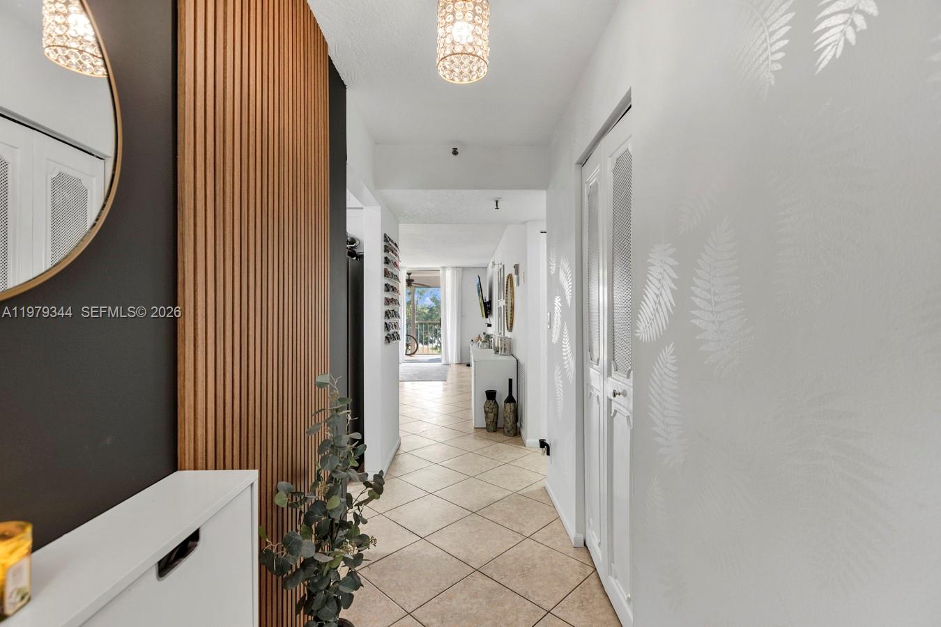 A hallway with tile flooring, a wood-slat accent wall, and a white door with mesh — 4550 NW 18th Ave # 206, Deerfield Beach FL 33064, DEERFIELD BEACH, FL