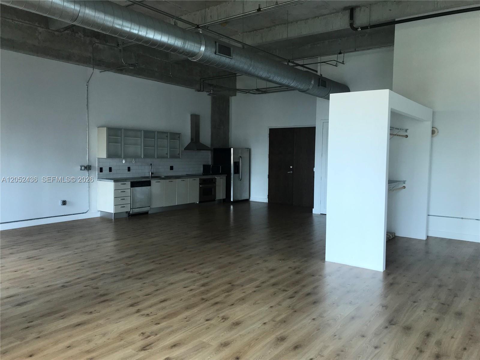 An open-concept loft kitchen features stainless steel appliances, white cabinetry, and exposed industrial ceiling ductwork — 1749 NE Miami Ct # 413, Miami FL 33132, MIAMI, FL