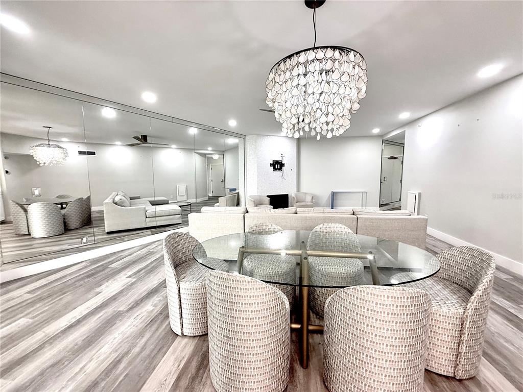 A dining area with a glass table and textured chairs sits before a mirrored wall — 1600 GULF BOULEVARD UNIT 1112, CLEARWATER BEACH, FL