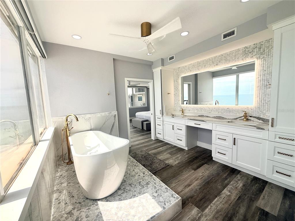 A modern bathroom features a freestanding tub, double vanity, and marble-style tile flooring — 1600 GULF BOULEVARD UNIT 1112, CLEARWATER BEACH, FL