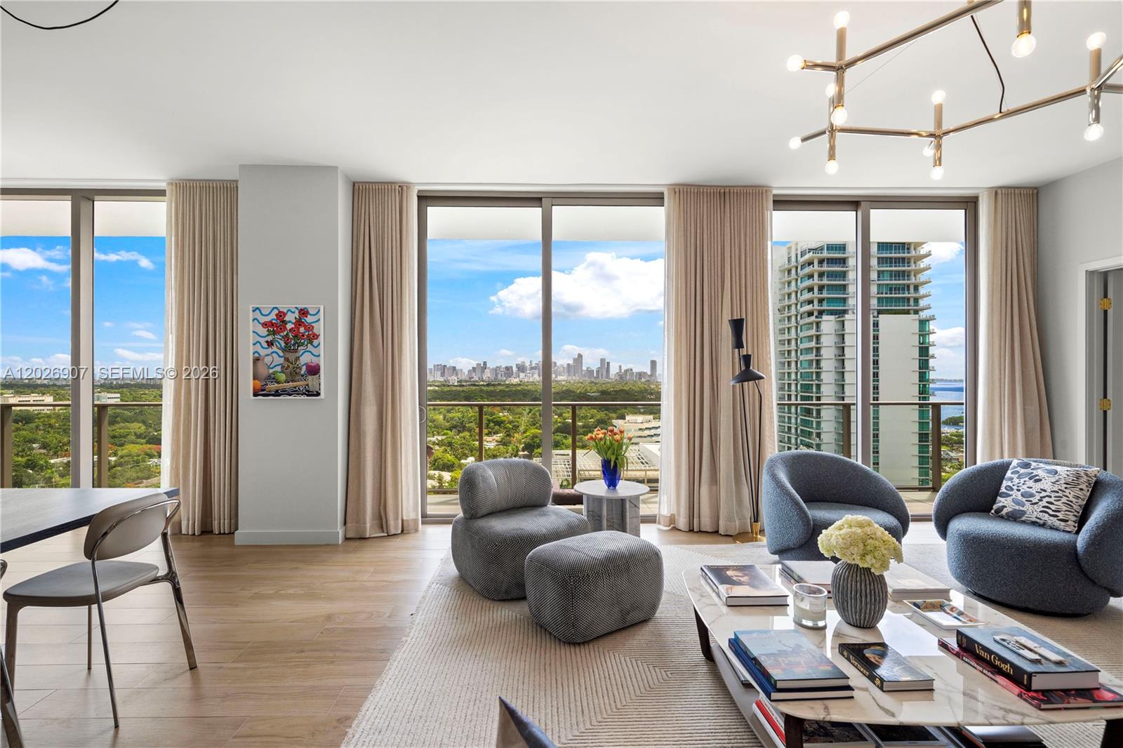 A modern living room features floor-to-ceiling windows with city views and contemporary furniture — 2678 Tigertail Ave # 1702, Miami FL 33133, MIAMI, FL