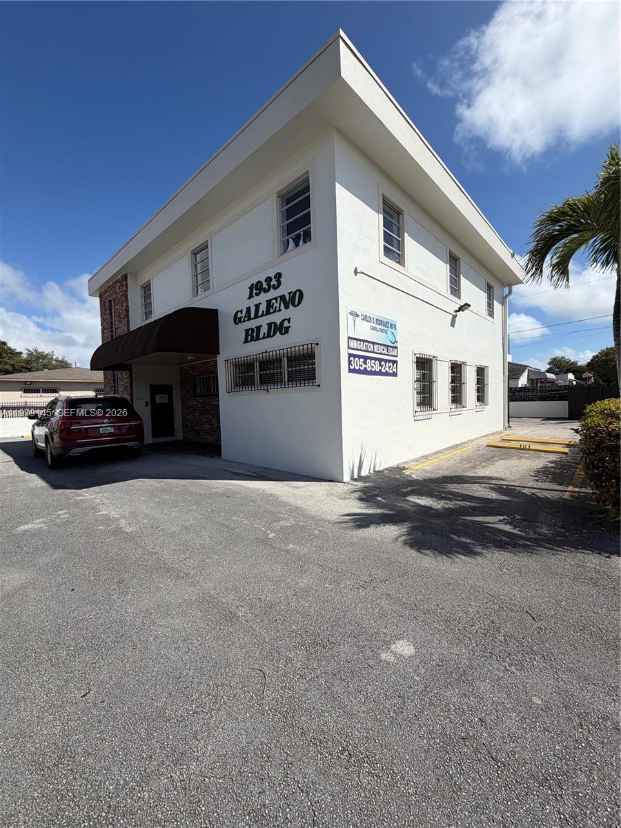 A two-story white commercial building with a parking lot and a red SUV parked outside — 1933 SW 27th Ave, Miami FL 33145, MIAMI, FL