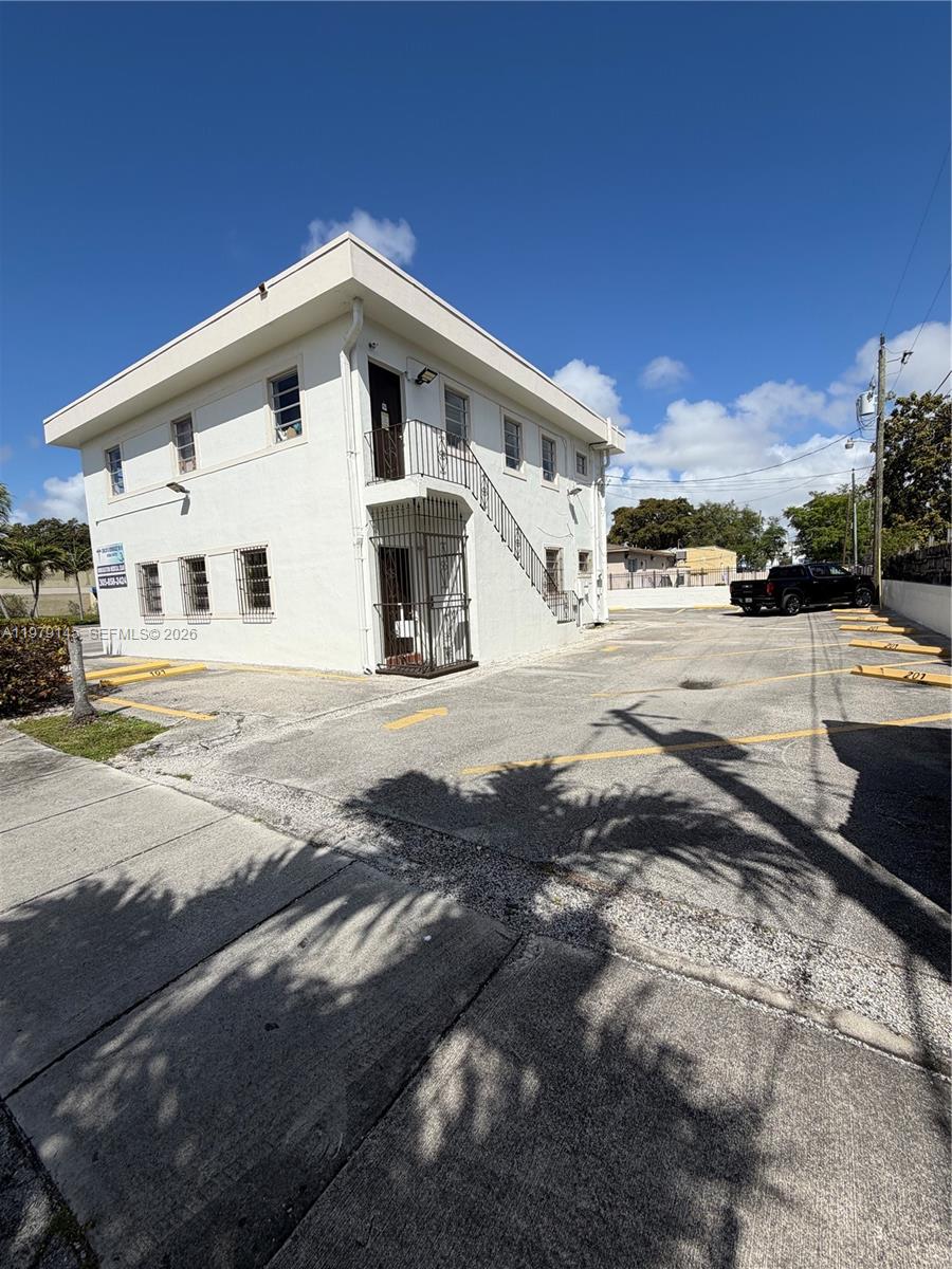 A two-story white commercial building features an exterior staircase and an adjacent paved parking lot — 1933 SW 27th Ave, Miami FL 33145, MIAMI, FL