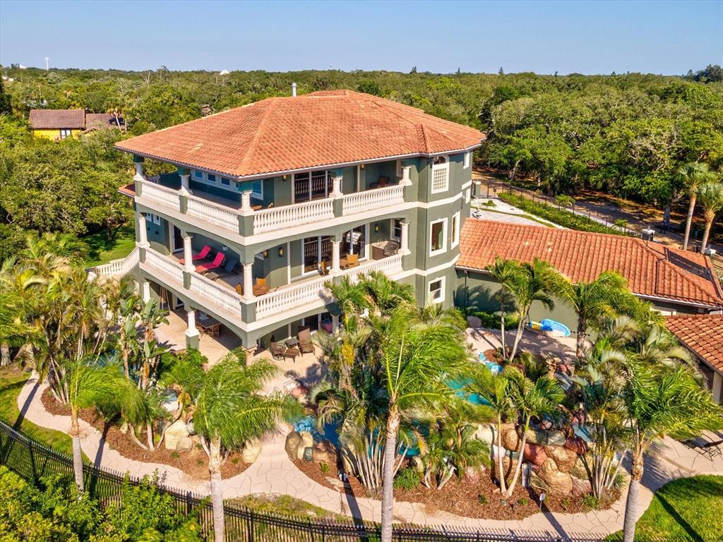 An aerial view of a three-story green house with a pool and palm trees — 15041 HARDAGE STREET, LARGO, FL