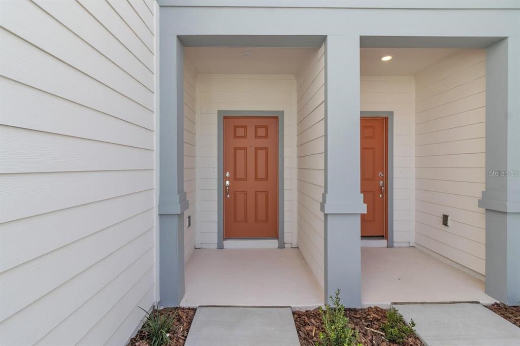 A view of two adjacent front doors with orange panels and gray trim — 2743 FETCHING TRL, DAVENPORT, FL