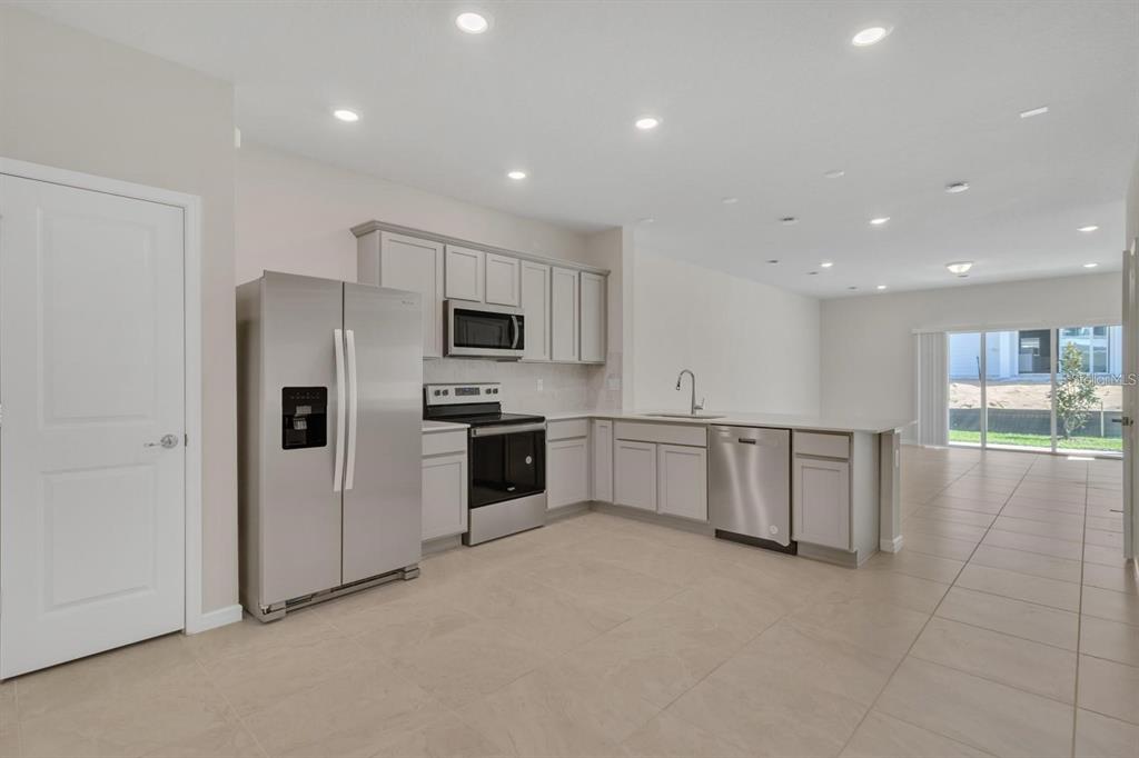 A modern kitchen with light gray cabinets, stainless steel appliances, and tile flooring — 2743 FETCHING TRL, DAVENPORT, FL