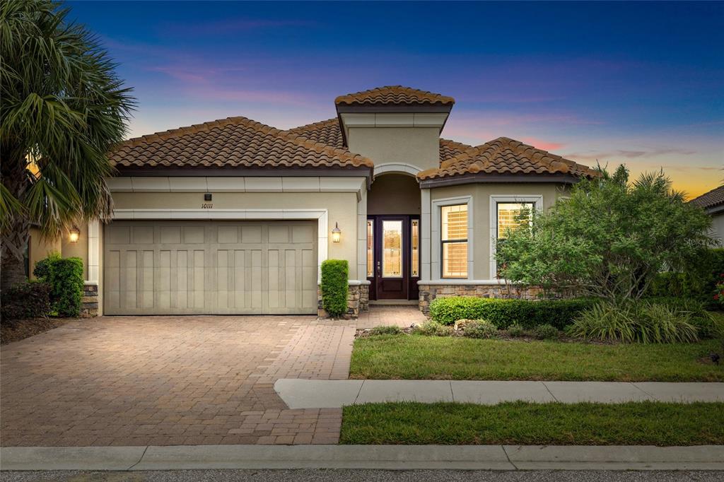 A single-story house with a tan stucco exterior, a tile roof, and a paved driveway — 10111 CRAFTSMAN PARK WAY, PALMETTO, FL