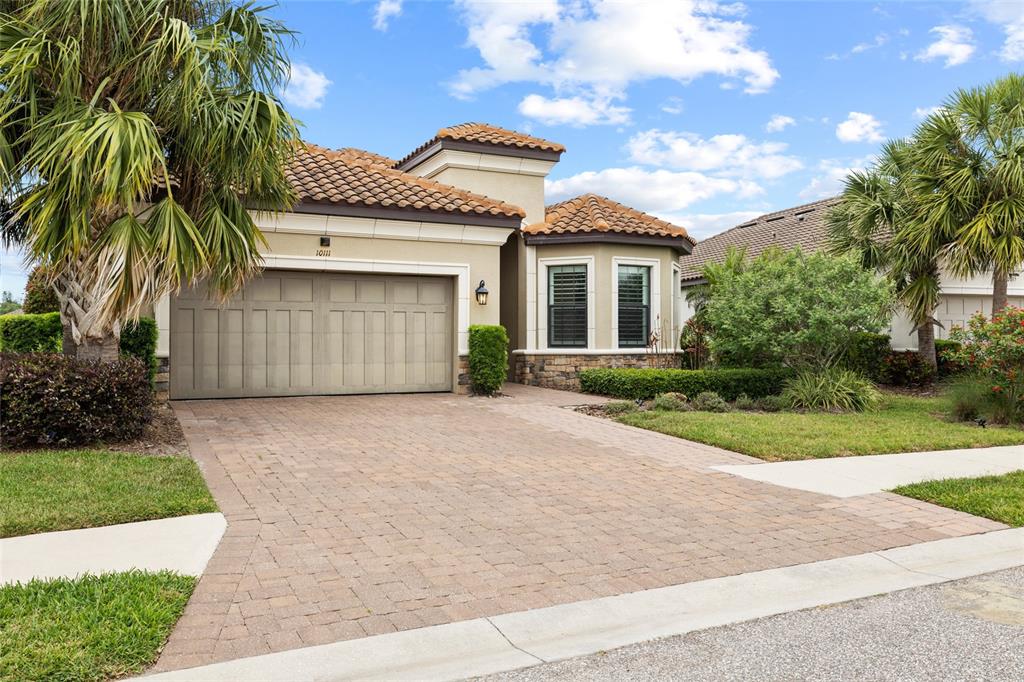 A single-story house with a tan stucco exterior, tile roof, and a paved driveway — 10111 CRAFTSMAN PARK WAY, PALMETTO, FL