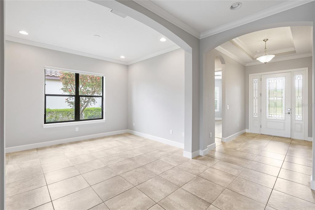A bright room with light tile flooring, an arched entryway, and a front door entrance — 10111 CRAFTSMAN PARK WAY, PALMETTO, FL