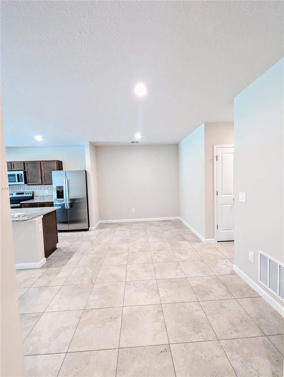 A kitchen with dark cabinets and stainless steel appliances opens into a tiled dining area — 285 Raspberry Road # 0, Fort Pierce FL 34981, FORT PIERCE, FL