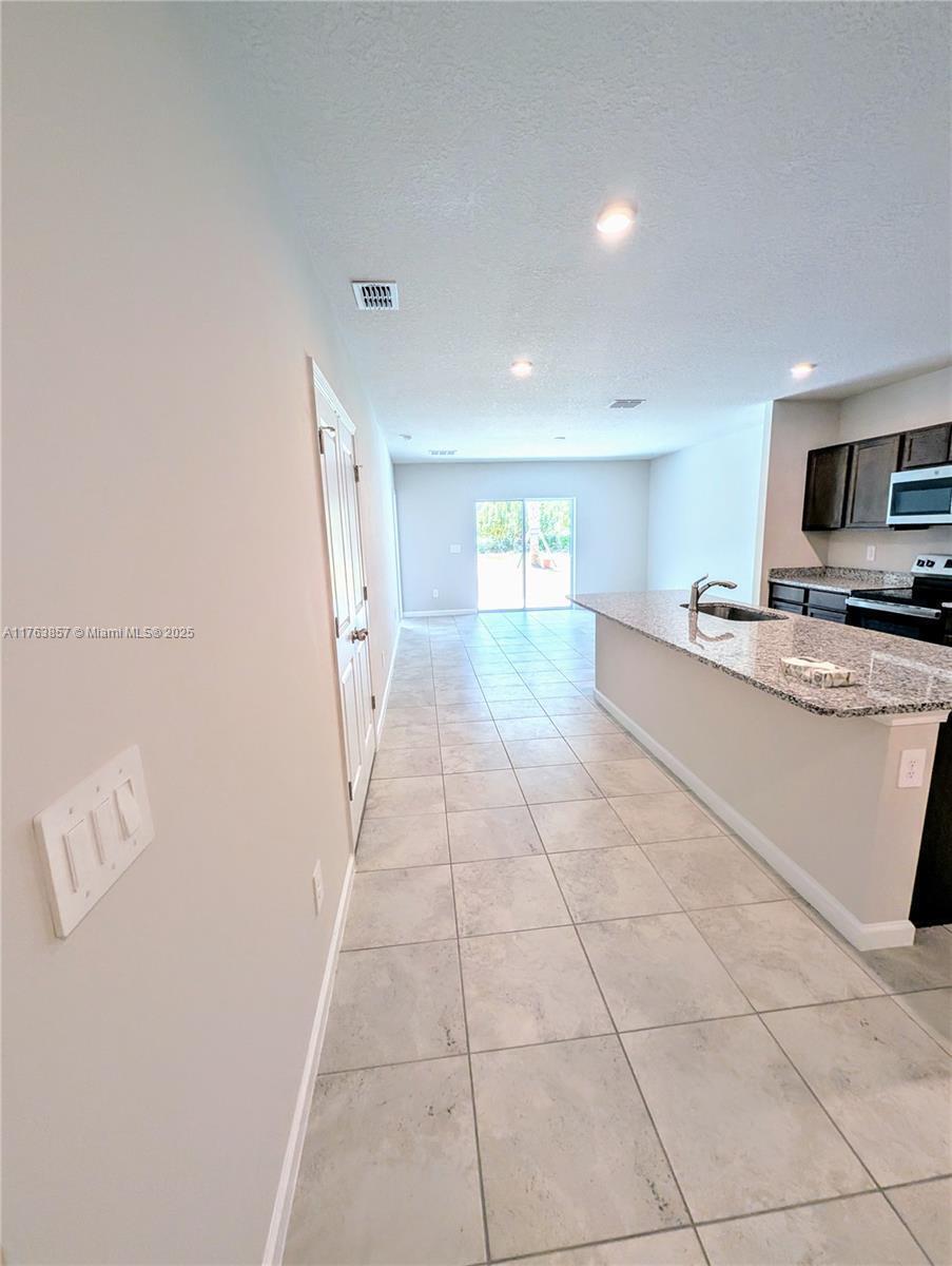 This kitchen features granite countertops, dark wood cabinets, and tile flooring leading to sliding doors — 285 Raspberry Road # 0, Fort Pierce FL 34981, FORT PIERCE, FL