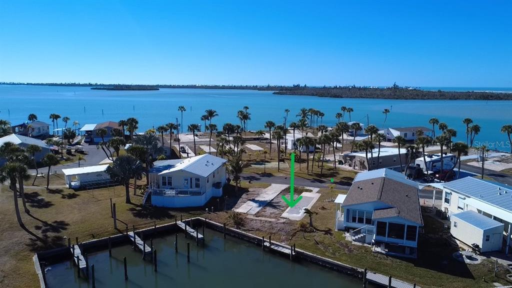 An aerial view shows a vacant waterfront lot with a concrete pad and boat dock — 7500 PARK POINTE DRIVE UNIT 45, ENGLEWOOD, FL