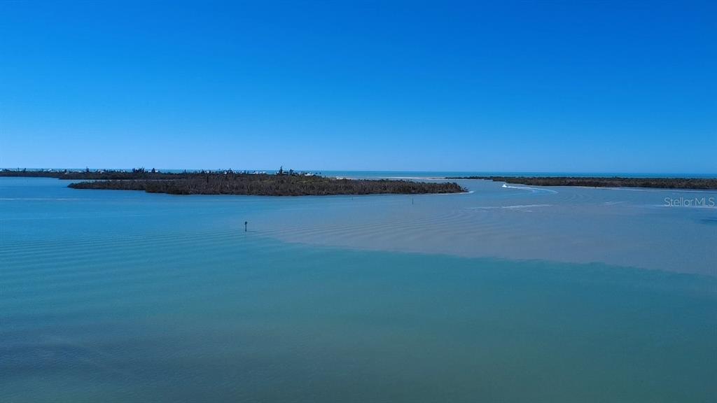 An aerial view shows a calm body of water meeting a small, wooded island — 7500 PARK POINTE DRIVE UNIT 45, ENGLEWOOD, FL